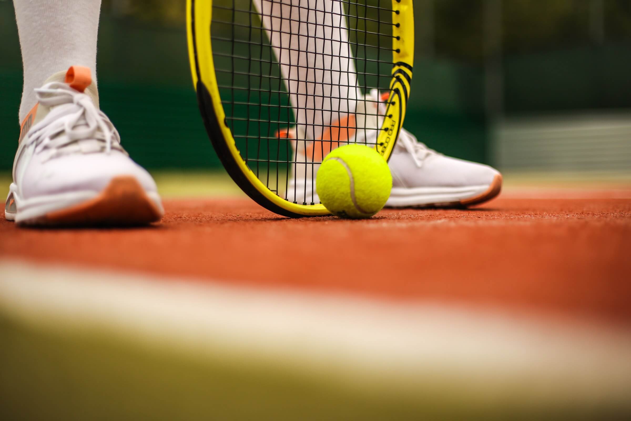 Close up of tennis player's feet standing over tennis ball