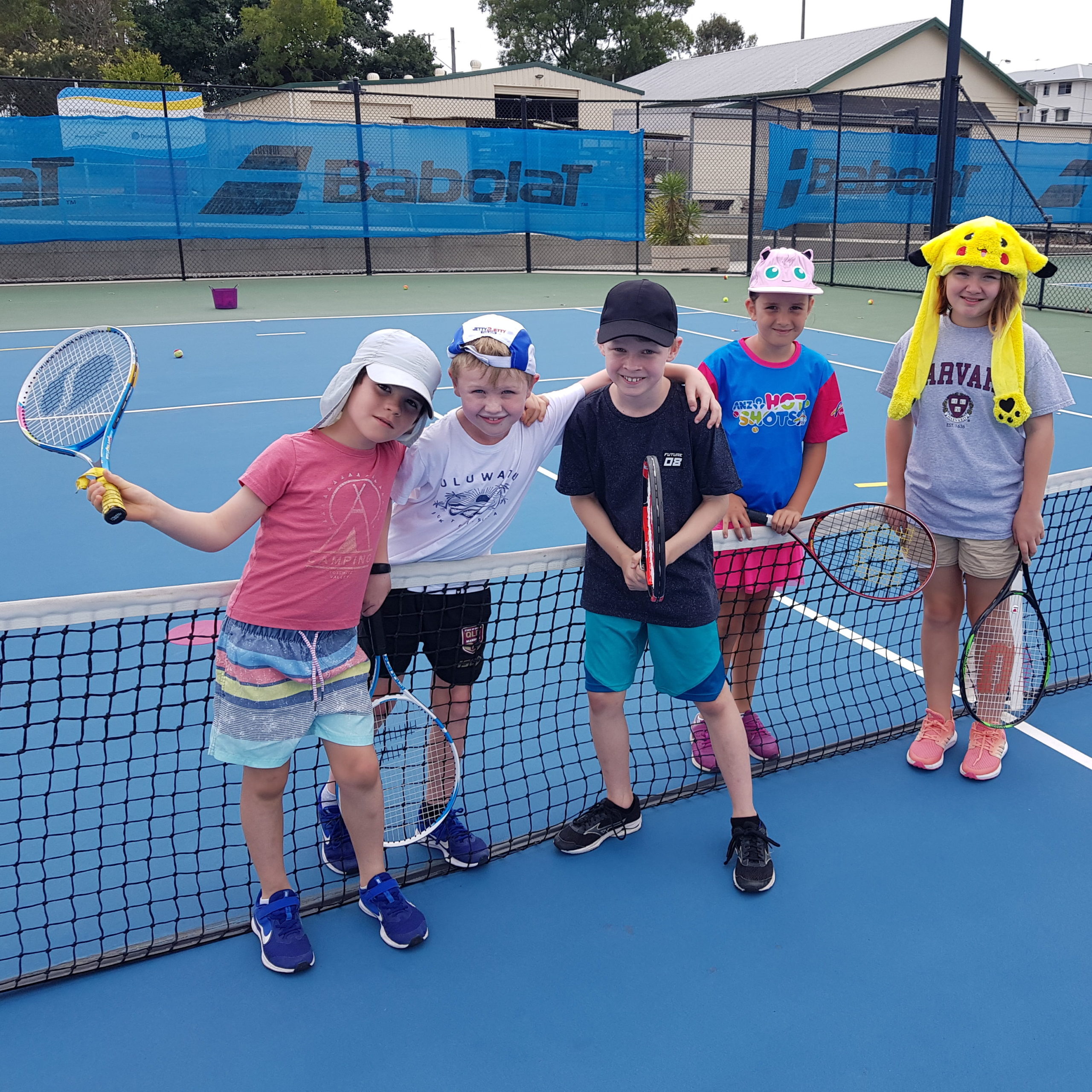 Kids smiling on tennis court at holiday school holiday tennis clinic